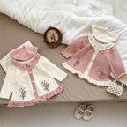 Children's pink and white outfit with matching hat on a bed